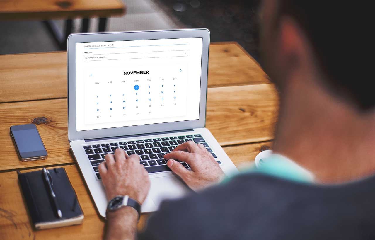man with laptop in front of him using an online scheduler to make an appointment